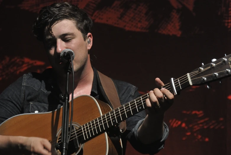 a male in a black shirt is playing the guitar