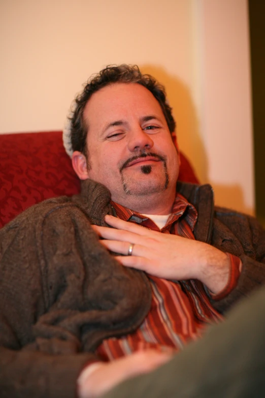 a man sitting on top of a couch next to a pillow