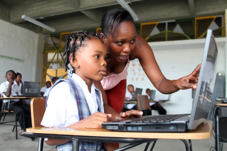 a woman using a computer with a child on her lap