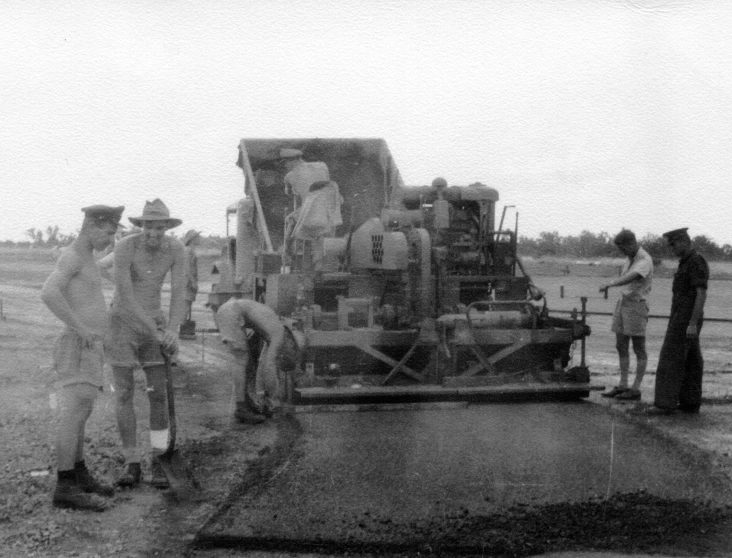 people standing around a large machine on a farm