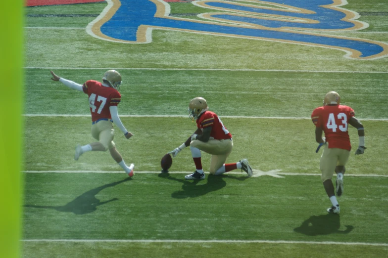 three football players in uniforms, with arms outstretched on the field