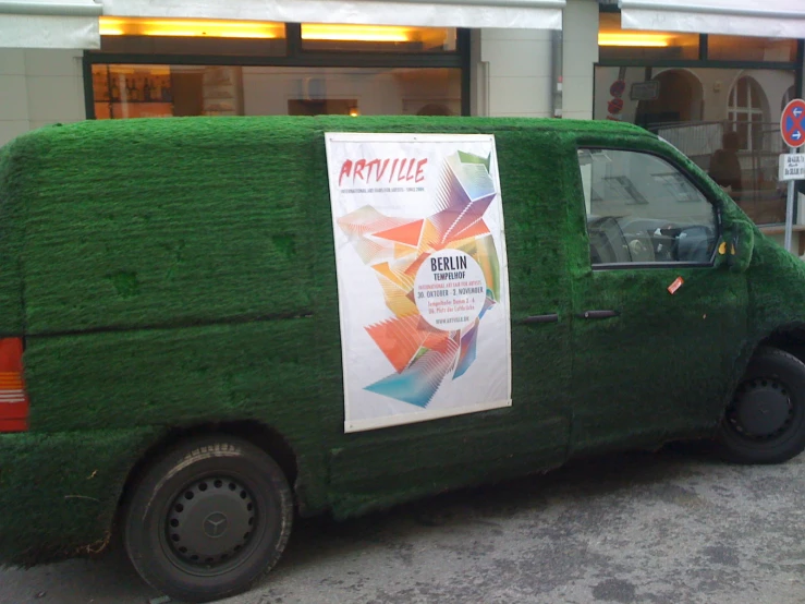 a car covered with grass is parked on the street