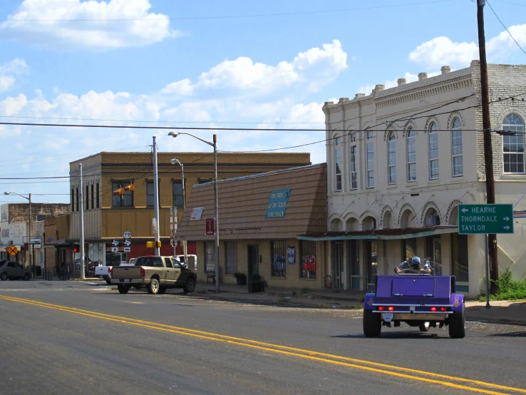 the city street has small old buildings and cars