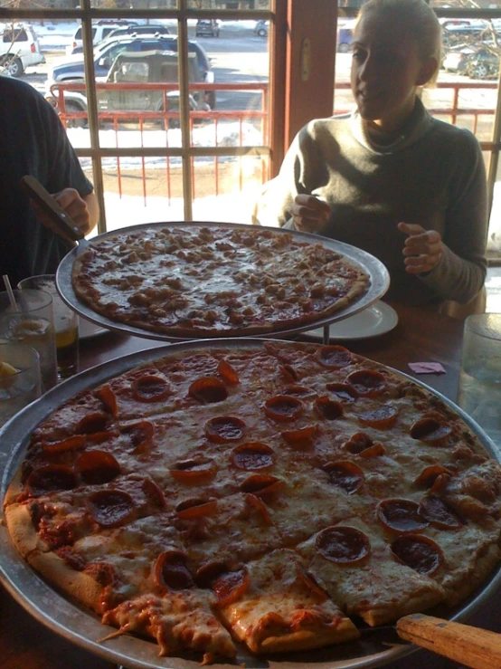 pizza in two pans sitting on top of a table