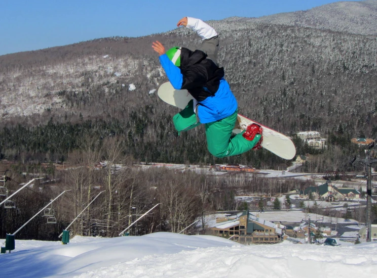 snow boarder doing aerial trick in front of snowy mountains