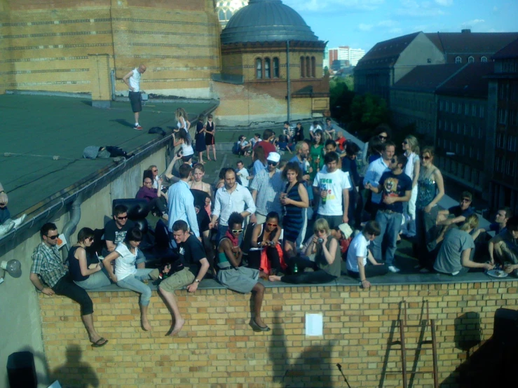 a crowd of people sitting on top of a brick building