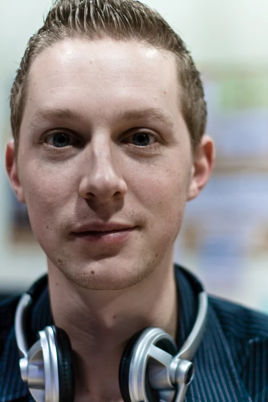 a man wearing silver headphones standing in front of a tv