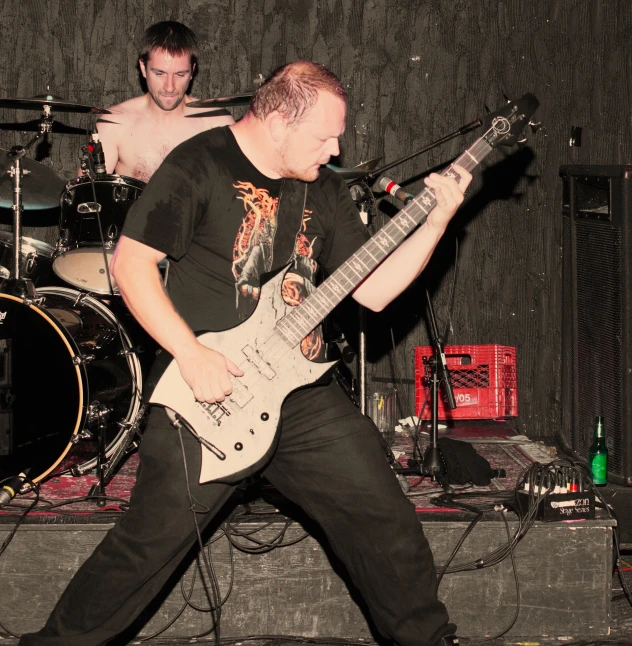 a man playing guitar while another watches