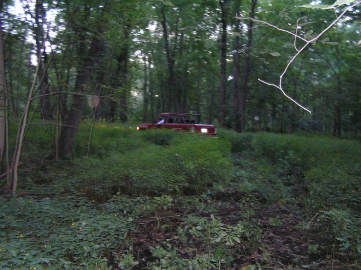 an old vehicle parked in the woods next to a pile of dirt