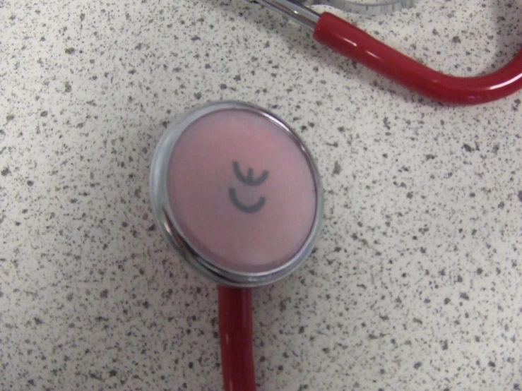 a red stethoscope laying on top of a pink object
