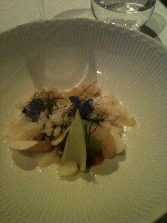 a dish with an artistic decoration on top sits in a white plate on a table