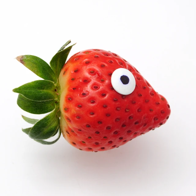 a strawberries with eyes and a leaf