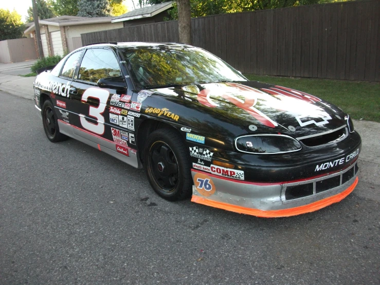 the car is parked on the street near the fence