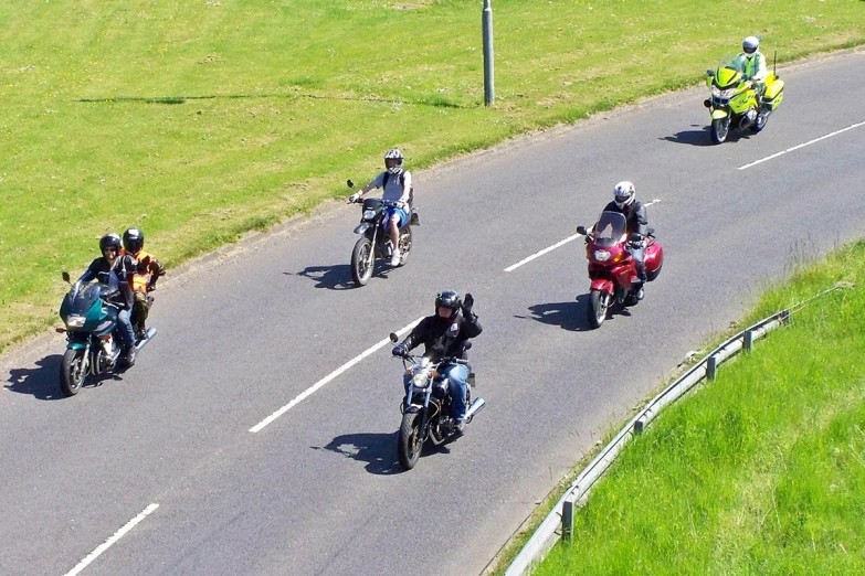 a group of people riding on the back of motorcycles down a road