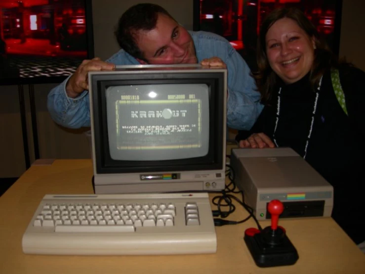 the man smiles with his hand on the shoulder as he next to an older computer
