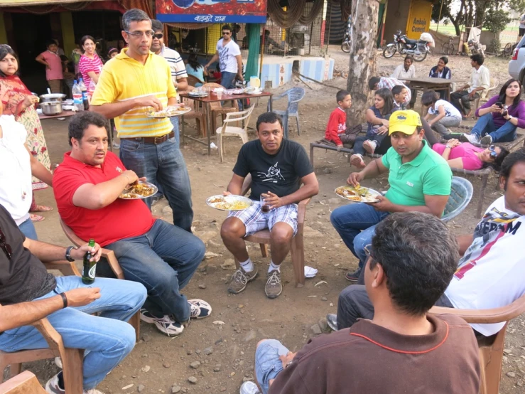 a group of people sitting in chairs while some eat food