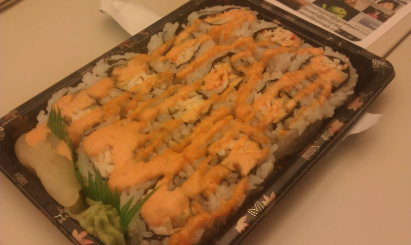 a large tray of sushi with sauce on it