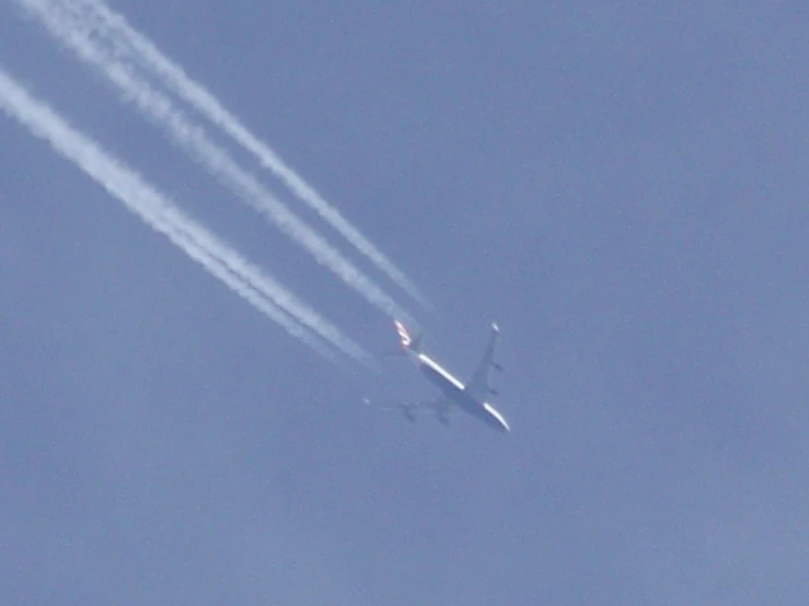 an airplane with four trailing jets in the air