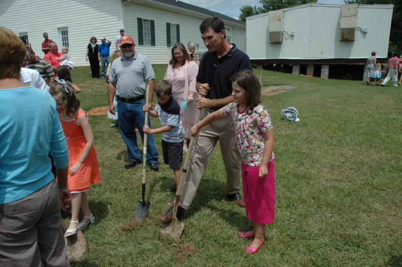 a group of people standing in a yard holding shovels