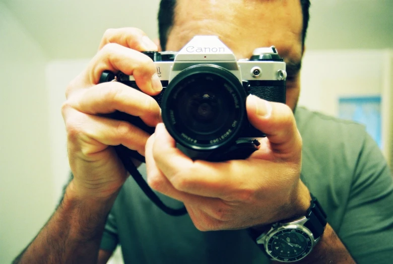 a man in a grey shirt holding up a camera