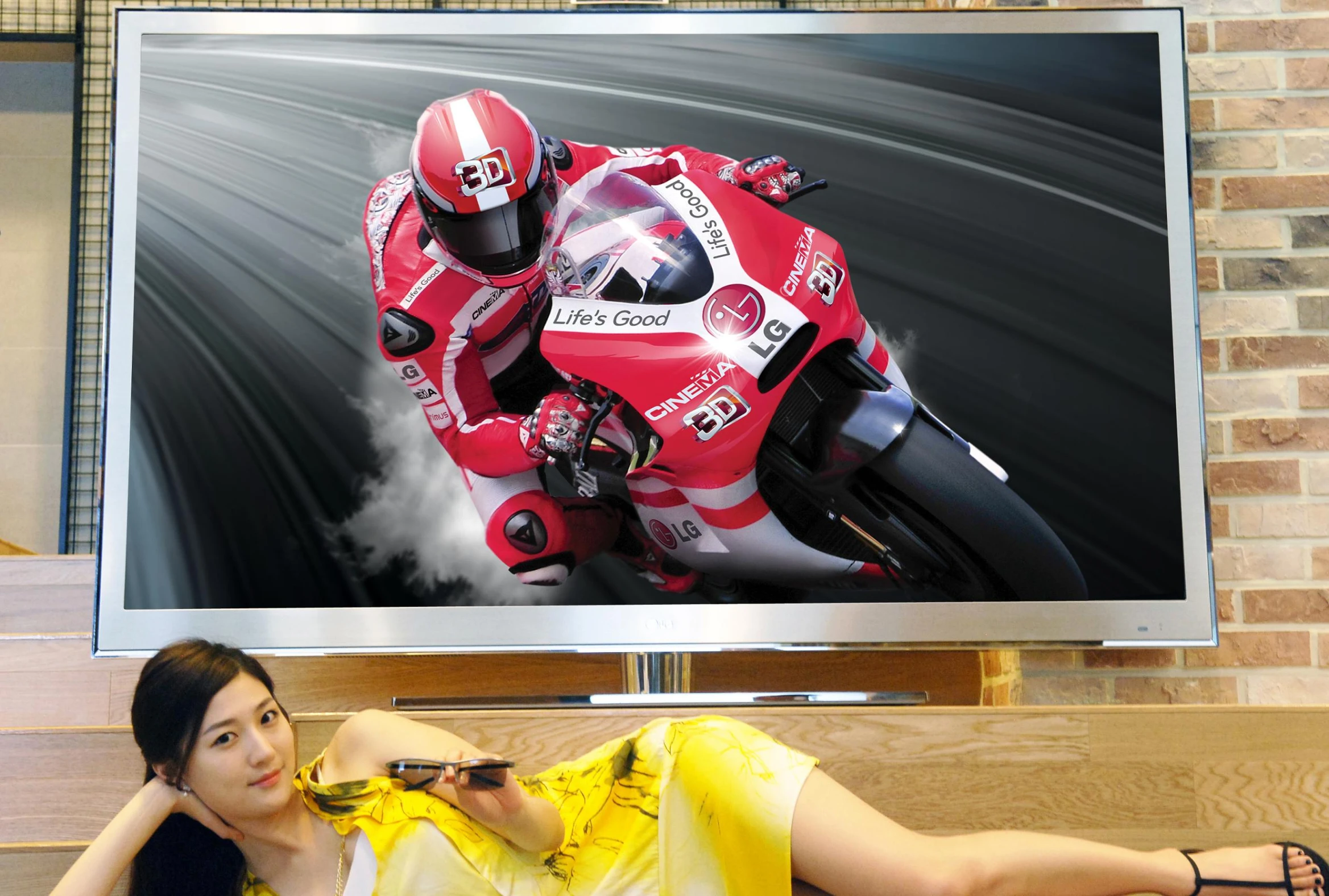 a woman is sitting and leaning against a wall in front of a television with a motorcycle image on it