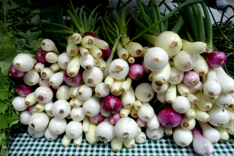 bunches of white garlic sit on a table at the market