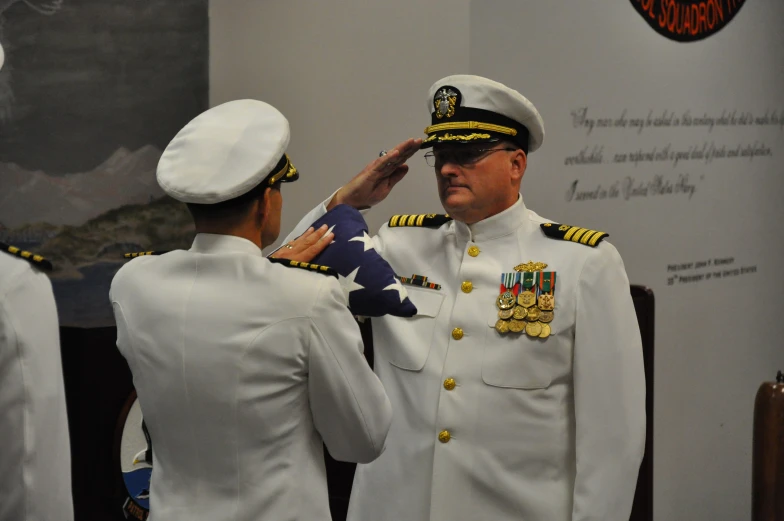 a man in military uniform is adjusting the uniform of another man