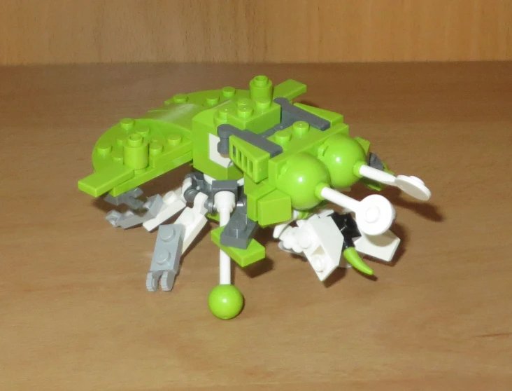 a lego robot with multiple green parts standing on top of the table