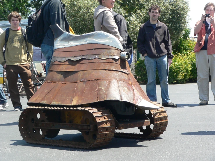 some people are standing around a rusty object