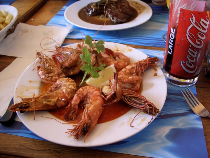 plate of cooked shrimp, red wine, and fries sitting next to coke