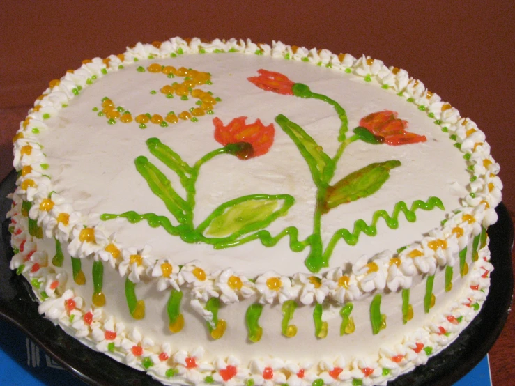 a birthday cake with icing, flowers, and leaves on it