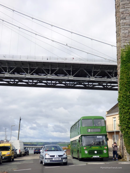 a green bus and some cars and a bridge