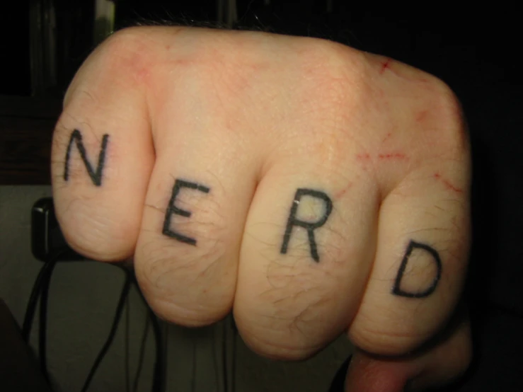 a person with the word nerd tattooed on their fingers