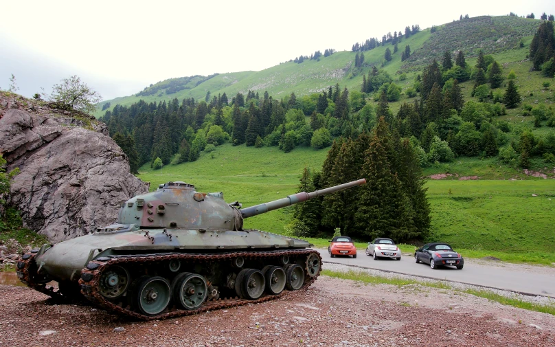 an old tank sitting on the road in front of some cars