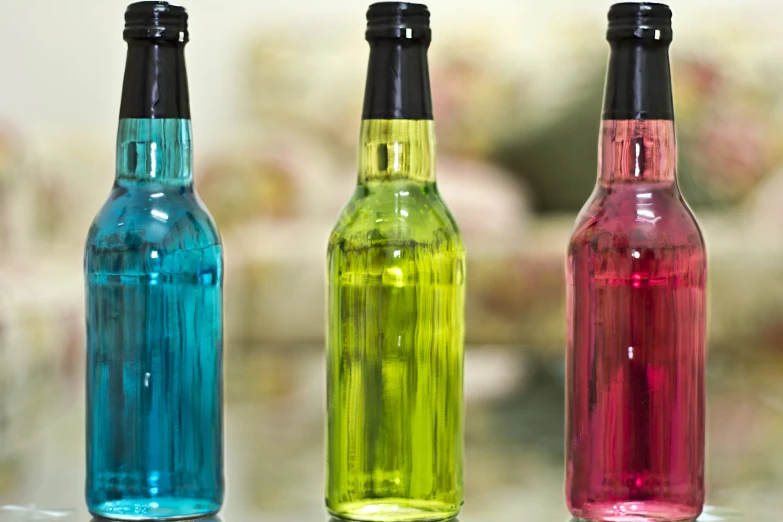 three bottles with different colors standing in line
