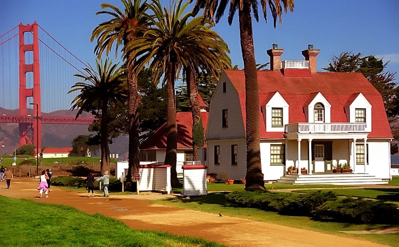 two people are walking on a pathway near a house near the golden gate bridge