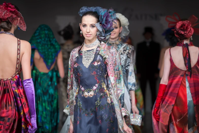 a row of women with colorful hats walking down a runway