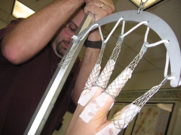 a man in purple shirt fixing a basketball hoop