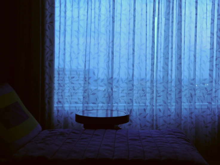 the bed is next to a window with blue curtains