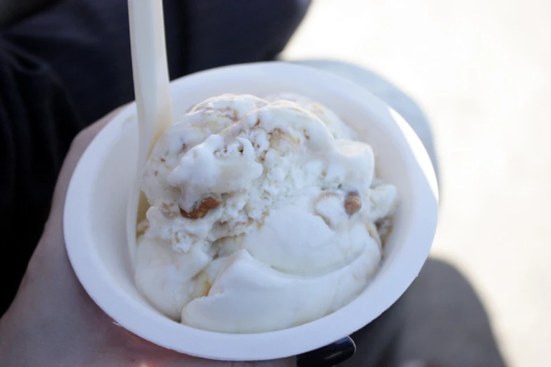 there is a person holding a paper bowl with ice cream