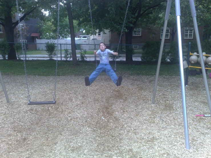 a man swinging on a swing in a park