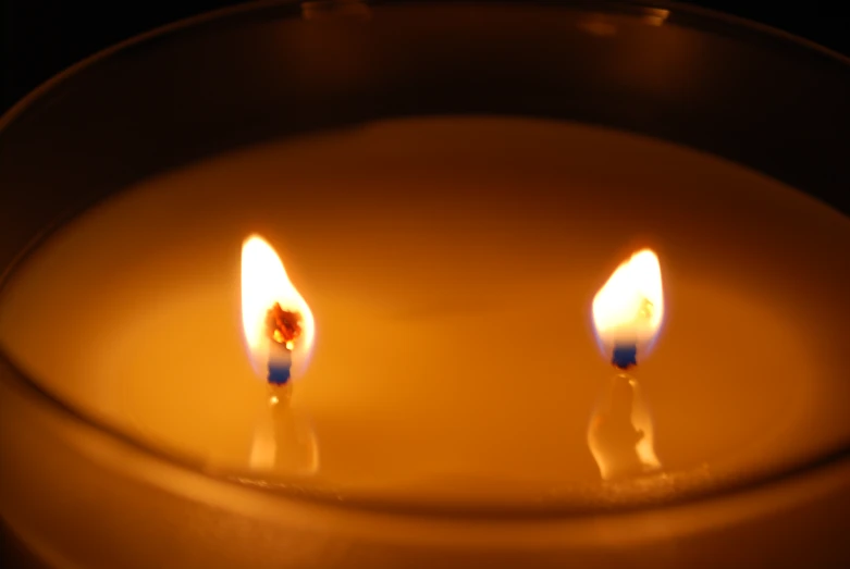 two candles burning next to each other on top of a plate