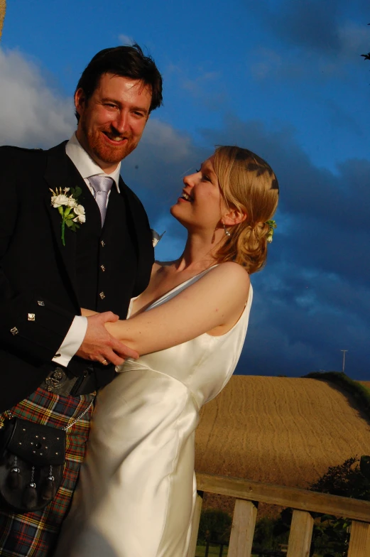 a bride and groom are posing with a scottish bag