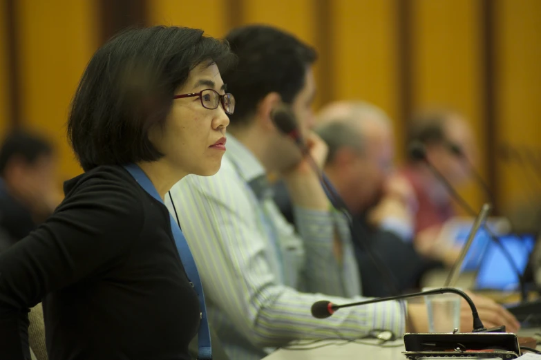 the woman is sitting in front of the microphone in front of the others