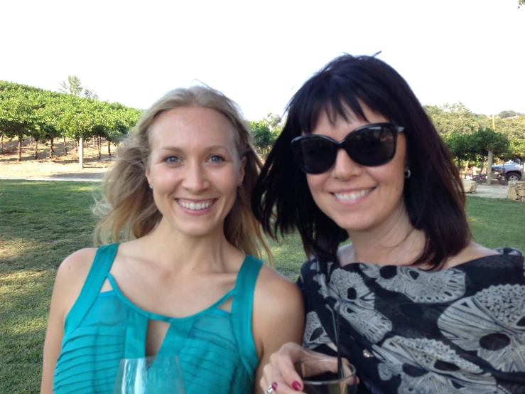 two women stand together in a park