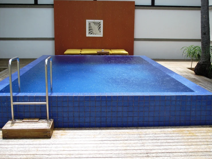 an empty swimming pool surrounded by wooden flooring