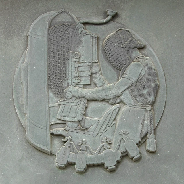 a carving depicts an old man operating a machine