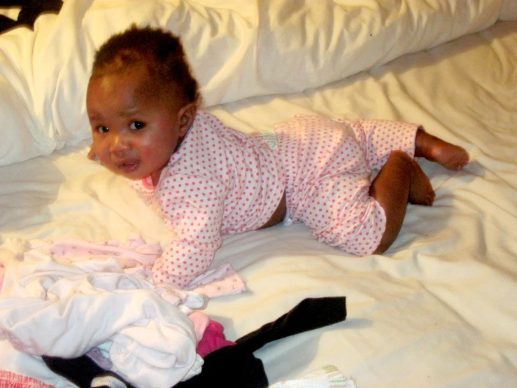 a young baby is lying on a bed with many clothes