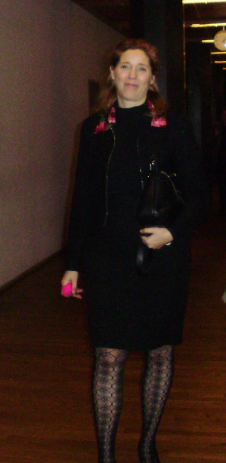 a woman in black dress with polka dot and pink accessories standing on hardwood floor