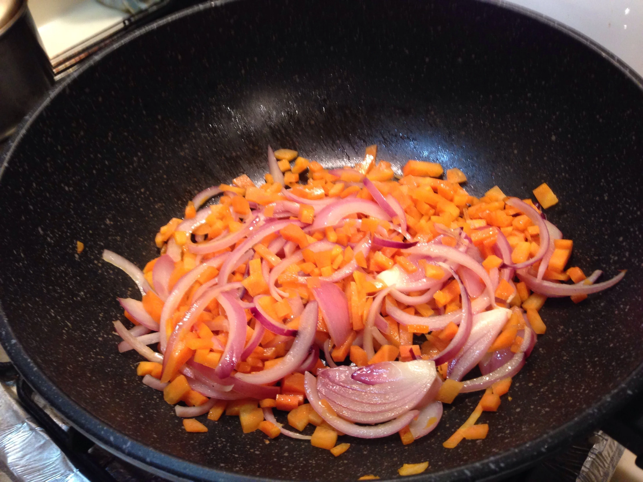 onions and carrots are cooking in a wok